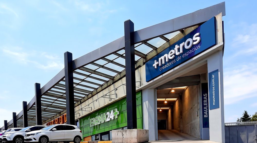 El acceso a las bauleras en Toscas Premium, al lado de la farmacia, con el cartel de +Metros sobre el portón