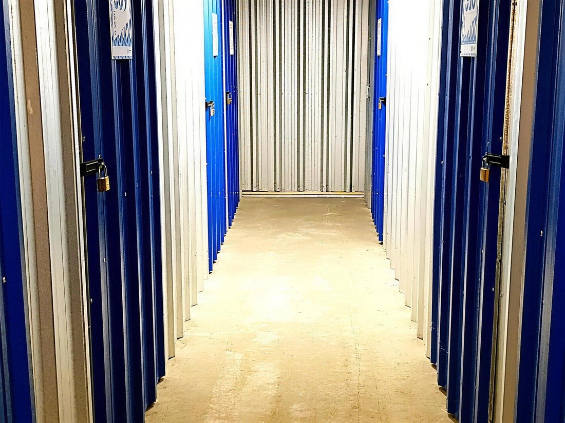Pasillo de bauleras de la sucursal de Almagro, con puertas azules, candados y una unidad abierta al fondo
